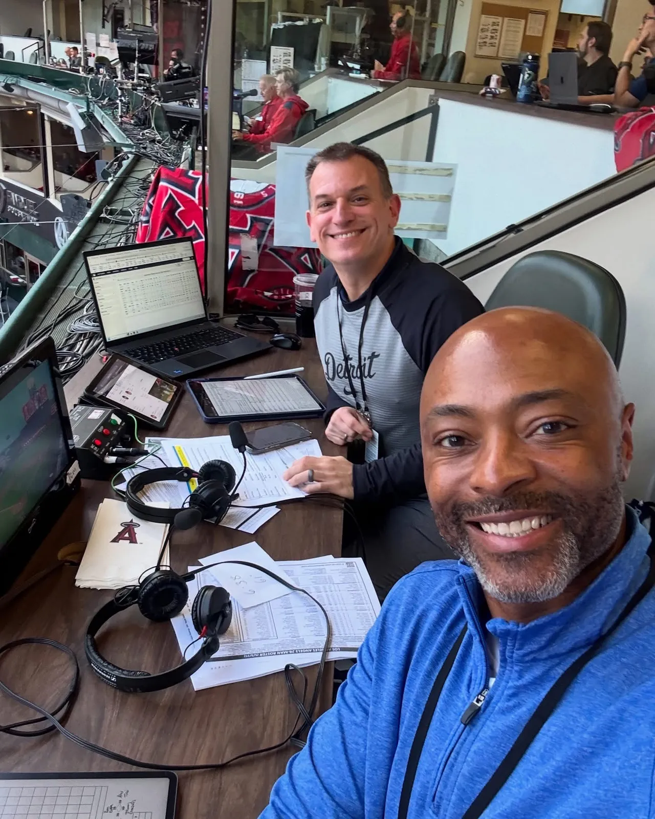Greg Gania and his broadcast partner smiling in the radio booth at Angel Stadium